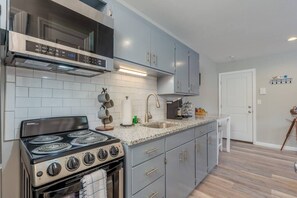 Een moderne keuken met een ingebouwde kookplaat, een roestvrijstalen oven en grijze kastjes.
