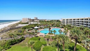 Un resort con una grande piscina, palme e vista sulla spiaggia.