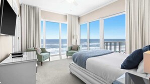 Una camera d'albergo con un letto grande, una scrivania, una sedia e vista sull'oceano.