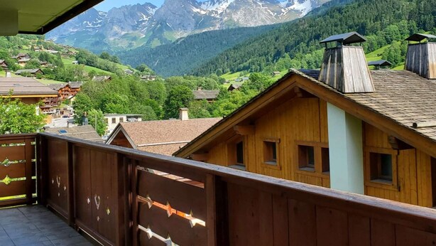 A wooden building with a balcony overlooking a mountainous landscape. - Rés Aravis C19 : Pistes et Cœur de Village à 3 min à Pied + Terrasse et Vue (LE GRAND BORNAND)