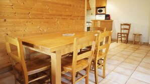 A wooden dining table with four chairs in a room with wooden walls and tiled flooring. - Rés Aravis C19 : Pistes et Cœur de Village à 3 min à Pied + Terrasse et Vue (LE GRAND BORNAND)