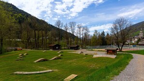 A rural landscape with a gravel path, wooden structures, and a mountain backdrop.