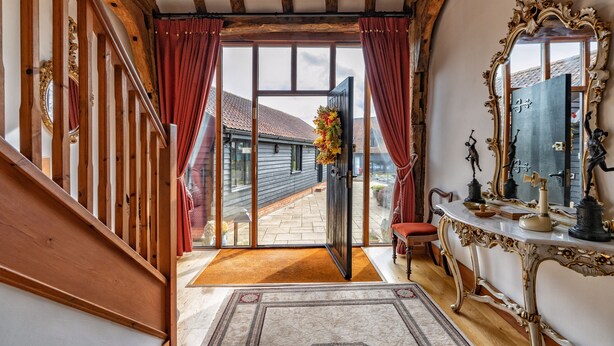 Una imponente escalera que conduce a una habitación con un espejo grande, piso de madera y vistas al exterior.