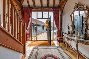 A grand staircase leading to a room with a large mirror, a wooden floor, and a view of the outside.