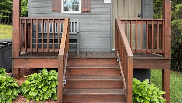Una baita di legno con veranda, un tappetino d'ingresso e un cartello che indica una caratteristica di sicurezza antincendio.