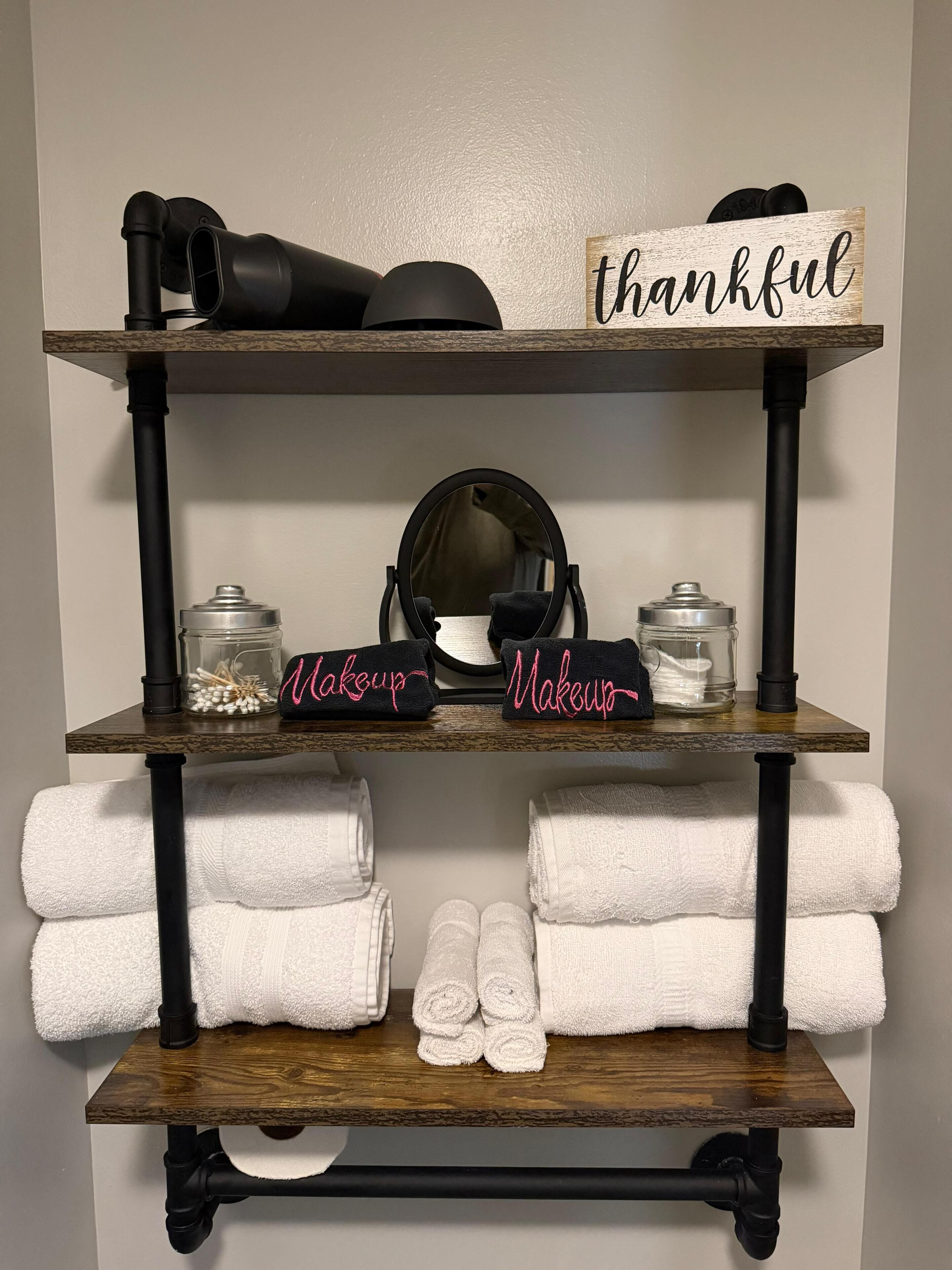 A shelf with makeup items, a mirror, and a 'thankful' sign.