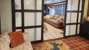 Um quarto com um painel deslizante shoji, um sofá com estampa, um tapete estampado e um ventilador de teto.