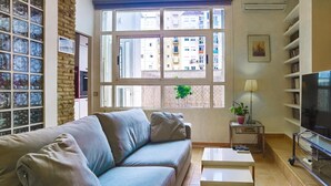 Ein Wohnzimmer mit Sofa, Couchtisch, Fernseher und Bücherregal.