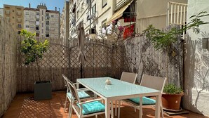 Eine Terrasse mit Tisch und Stühlen, einem Topfpflanzen und einem Bambuszaun.