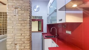 Eine Küche mit Backsteinwand, roter Arbeitsplatte und Spüle aus Edelstahl.