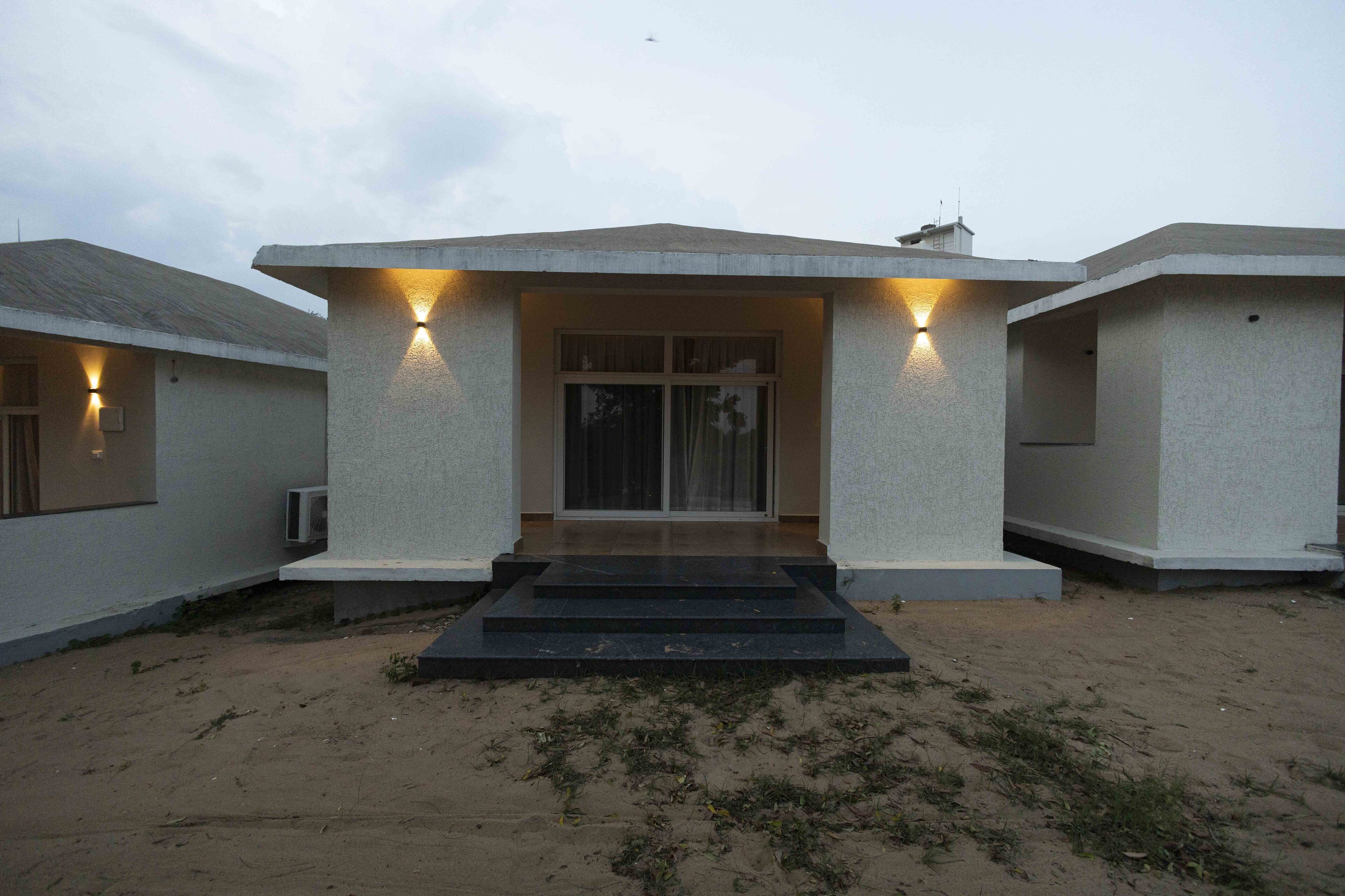 Un bâtiment moderne doté d’une façade en béton, d’une entrée principale avec une porte en verre et de deux entrées latérales éclairées.