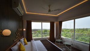 A modern hotel room with a large bed, a balcony with a view, and a ceiling fan. - SAMUDRA RESORTS AND SPA (Brahmagiri)