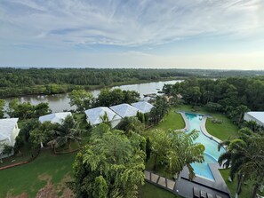 Un resort con piscina, abundante vegetación y un río al fondo.