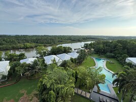 A resort with a swimming pool, lush greenery, and a river in the background.