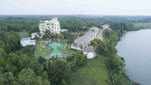 A resort with a swimming pool, multiple guest buildings, and a lake. - SAMUDRA RESORTS AND SPA (Brahmagiri)