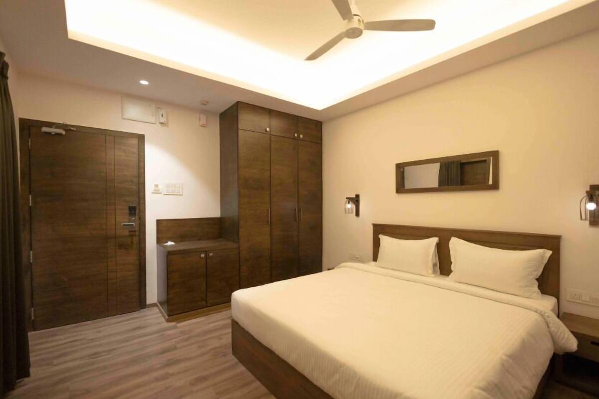 A bedroom with a bed, a wardrobe, a mirror, and a ceiling fan.