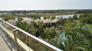 A view of a hotel with a pool, surrounded by lush greenery and a river in the background. - SAMUDRA RESORTS AND SPA (Brahmagiri)