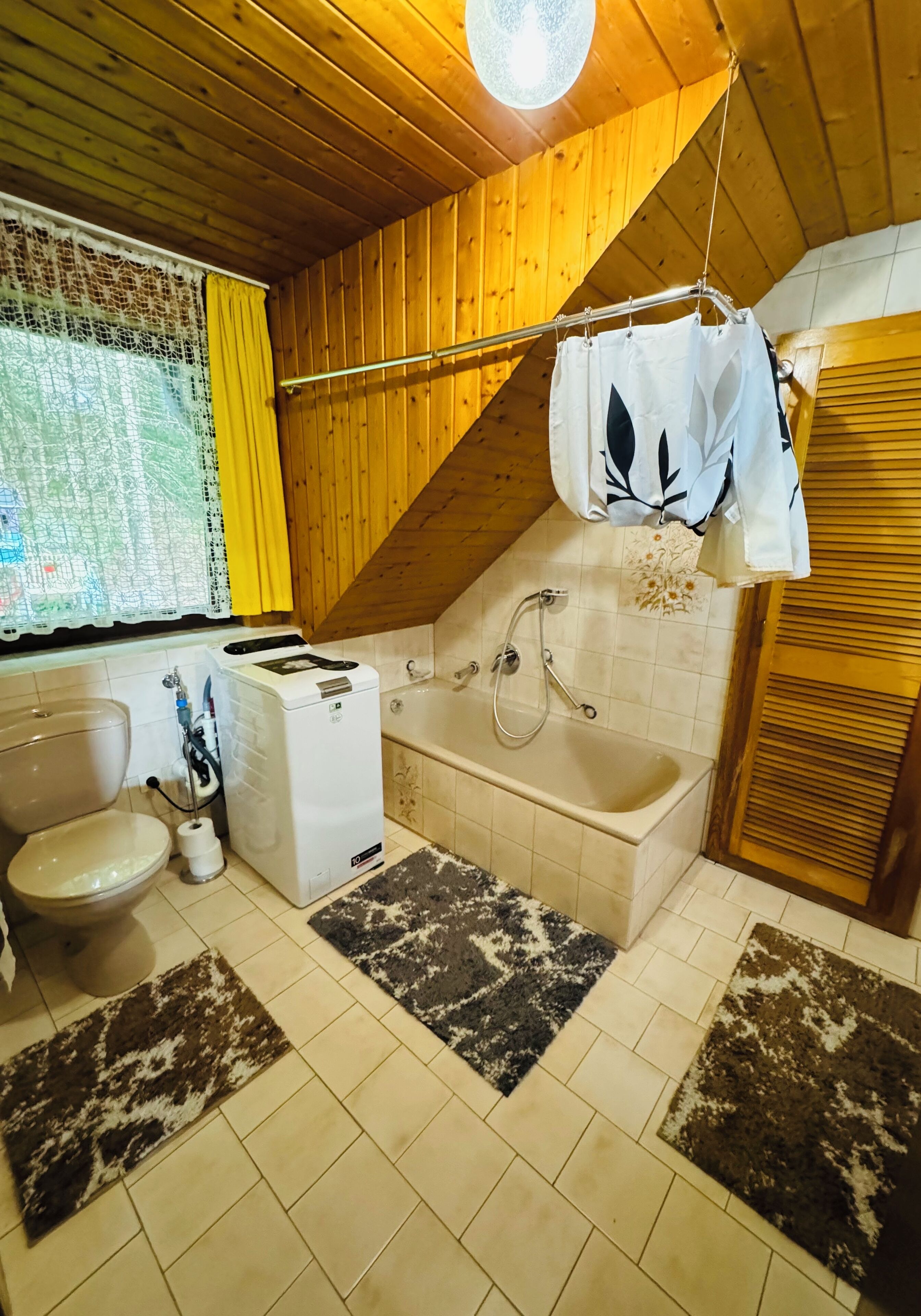 Un baño pequeño con inodoro, lavadora y bañera.