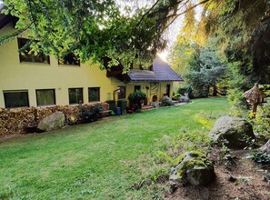 Une maison avec un mur en pierre, une cour gazonnée et une toiture en chaume.