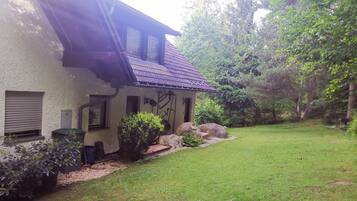 A house with a sloped roof, a small porch, and a well-maintained lawn.