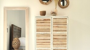 A room with a wooden wardrobe, a mirror, and a vase with dried flowers.