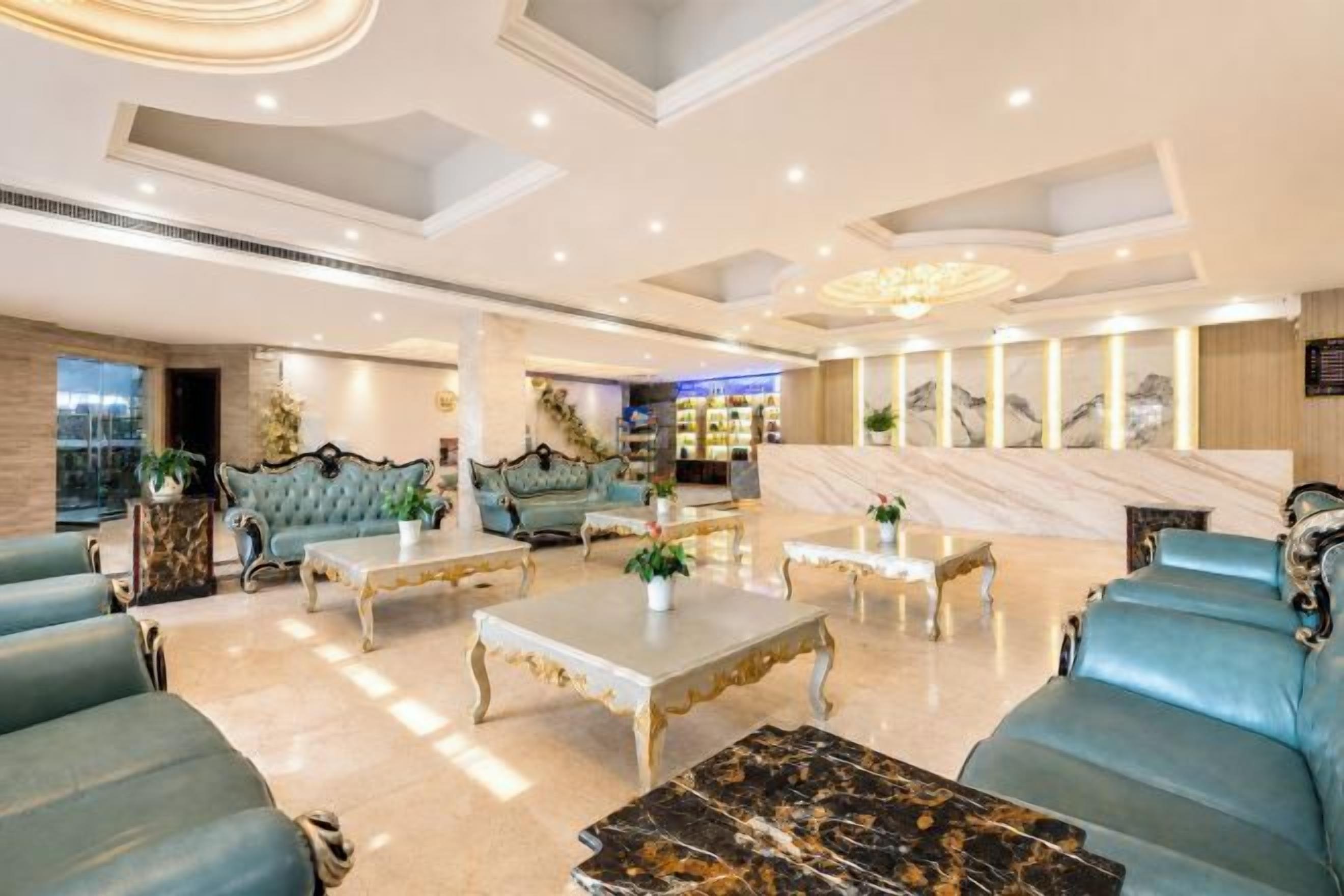 A spacious lobby with seating areas, a reception desk, and a marble wall with artwork.