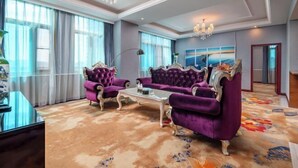 Una habitación amplia con un ventanal grande, un candelabro y un conjunto de sofás.