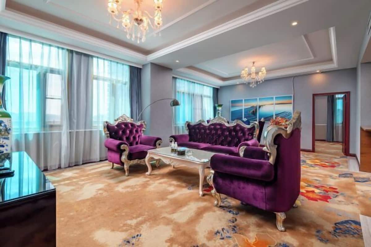 Ein geräumiges Zimmer mit großem Fenster, einer Chandelüster und einer Sofagarnitur.