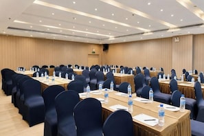 Un salón de conferencias con filas de mesas y sillas, equipado con botellas de agua y tarjetas de identificación.