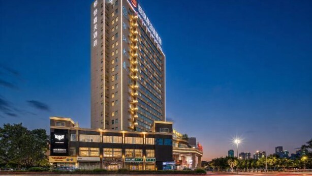 Un hotel alto con varios pisos, un cartel llamativo en la parte superior y una fachada bien iluminada.