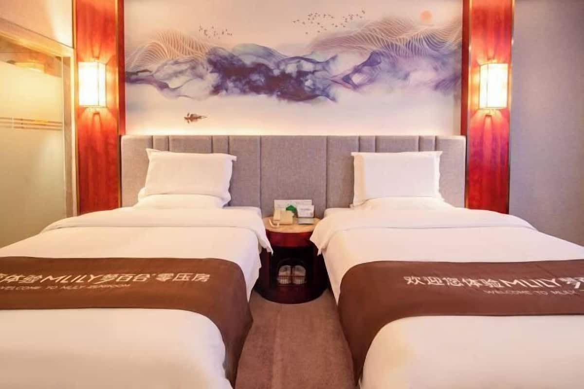 Ein Hotelzimmer mit zwei Betten, einem Nachttisch, einer Wandlampe und einem Wanddekor.