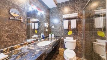 A bathroom with a marble sink, a toilet, and a shower area.