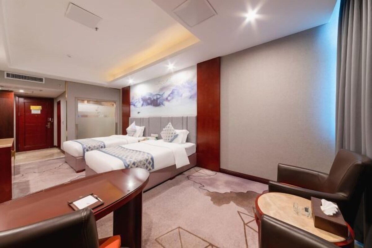 Ein Hotelzimmer mit einem Bett, einem Schreibtisch, einem Sessel und einem kleinen Tisch.