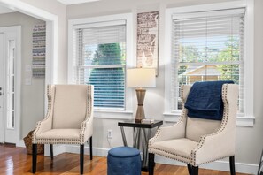 Relax in comfort with two tufted armchairs and a small table, featuring a lamp and decorative vase.