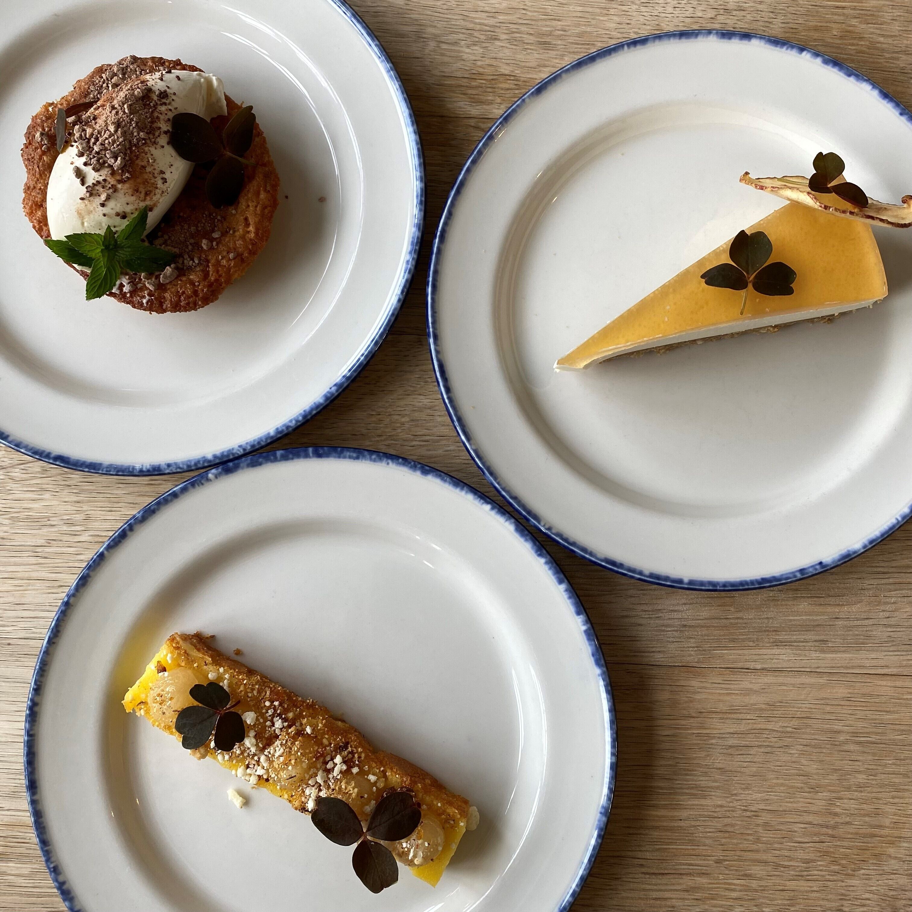 Trois assiettes contenant des desserts, posées sur une table en bois.