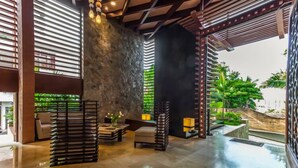 A spacious lobby with a stone wall, modern furniture, and a view of greenery outside. - Residences by Pinnacle Unit 501 3BD Condo for rent in Old Town, Puerto vallarta (Puerto Vallarta)