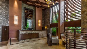 A reception area with a marble floor, a reception desk, and a seating area with a view of greenery through a patterned window. - Residences by Pinnacle Unit 501 3BD Condo for rent in Old Town, Puerto vallarta (Puerto Vallarta)