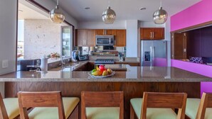 A modern kitchen with wooden cabinets, stainless steel appliances, and a central island with bar stools. - Residences by Pinnacle Unit 501 3BD Condo for rent in Old Town, Puerto vallarta (Puerto Vallarta)