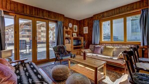 Ein gemütliches Wohnzimmer mit Holzwänden, einer Couch, einem Couchtisch und einem Bücherregal.