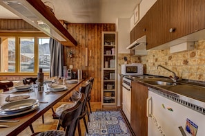 Una cocina con armarios de madera, un microondas y un comedor con una mesa dispuesta para cuatro.