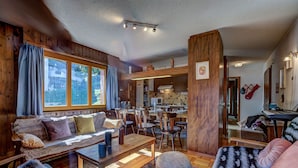Ein gemütliches Wohnzimmer mit einer Holzsofa, einem Couchtisch und einem Essbereich mit Stühlen.