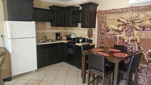 A kitchen with dark wooden cabinets, a white refrigerator, a stove, and a dining table with chairs. - Home away from home (San Felípe)