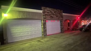 A garage with a white door, a stone wall, and a car parked inside. - Home away from home (San Felípe)