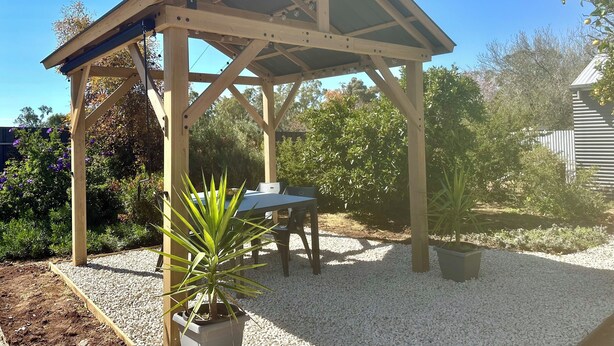 A wooden gazebo with a sloped roof, a table, and chairs underneath. - Baxter's Vintage Chic BnB (Clare)