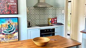 A kitchen with a wooden table, two stools, a tiled backsplash, and a stainless steel range hood. - Baxter's Vintage Chic BnB (Clare)
