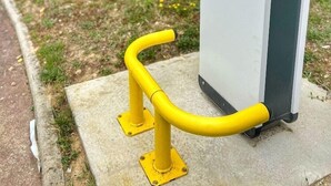 Ein Verteilerkasten mit einer gelben Handläufe vor einem Gebäude.
