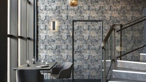 Ein modernes Interieur mit Treppe, Essbereich mit Tisch und Stühlen sowie einer Wand mit Muster.