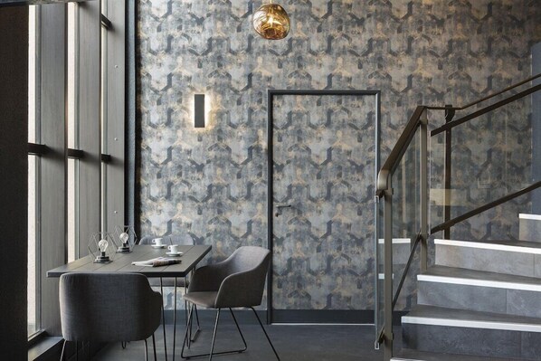 Ein modernes Interieur mit Treppe, Essbereich mit Tisch und Stühlen sowie einer Wand mit Muster.