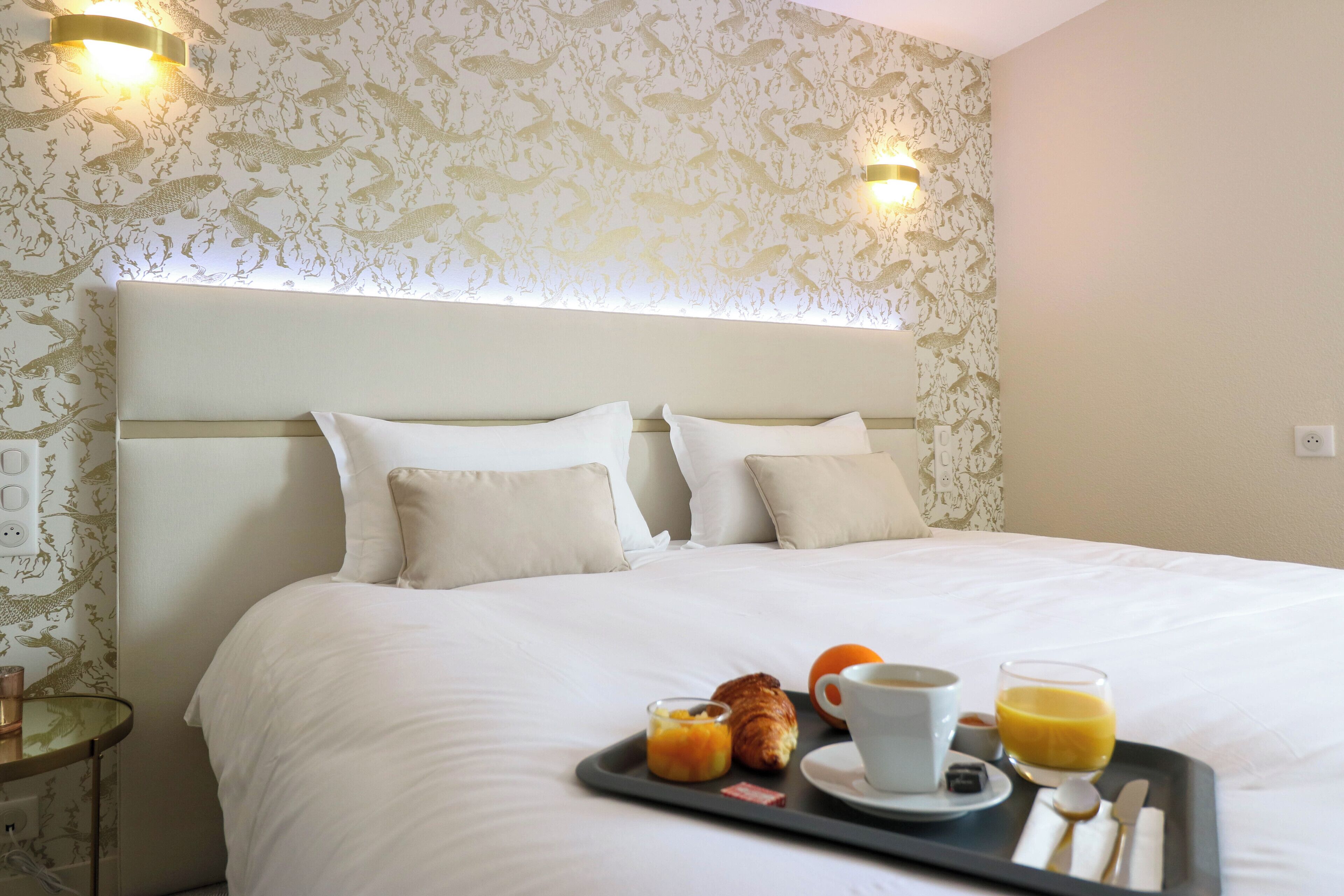 A neatly made bed with a tray of breakfast items including croissants, orange juice, and coffee.