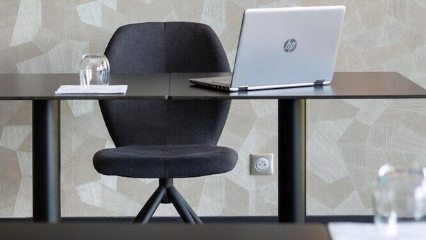 Un espace de bureau moderne avec un bureau en verre, une chaise noire et un ordinateur portable HP.